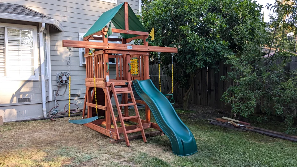 Gorilla wooden playset with a covered tower, green slide, swing, and trapeze, assembled by Artem in July 2024